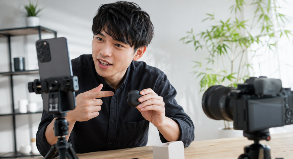 縦位置のスマートフォンとカメラを使いSNS向けの商品紹介動画を撮影する日本人クリエイター