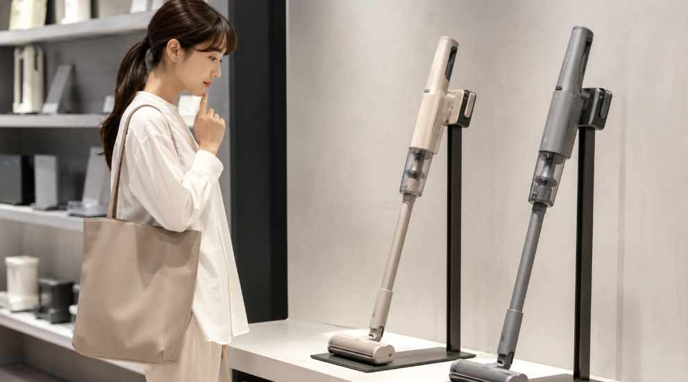 グレージュとグレーのコードレス掃除機を店頭で比較する日本人女性