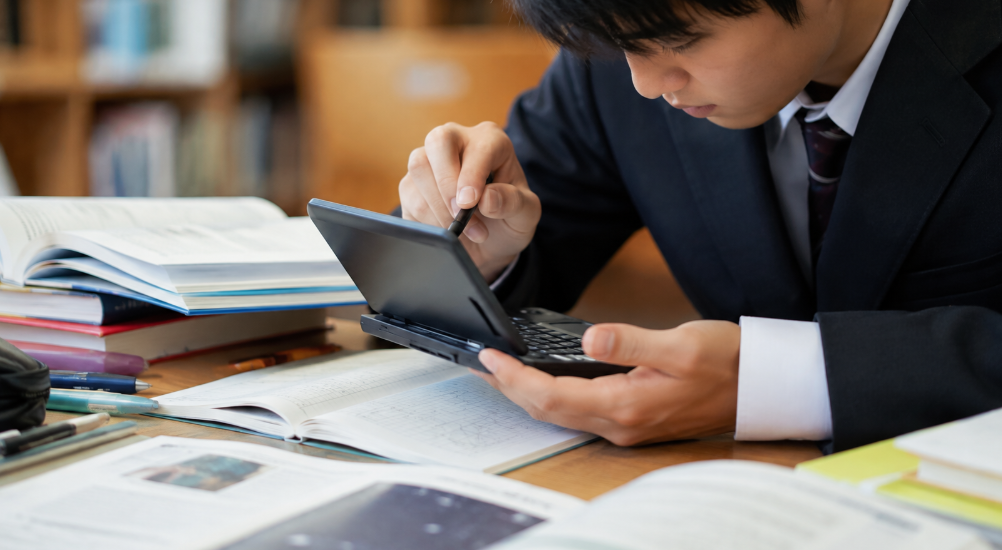 電子辞書を使いながら英語や受験科目を学習する日本人男子高校生