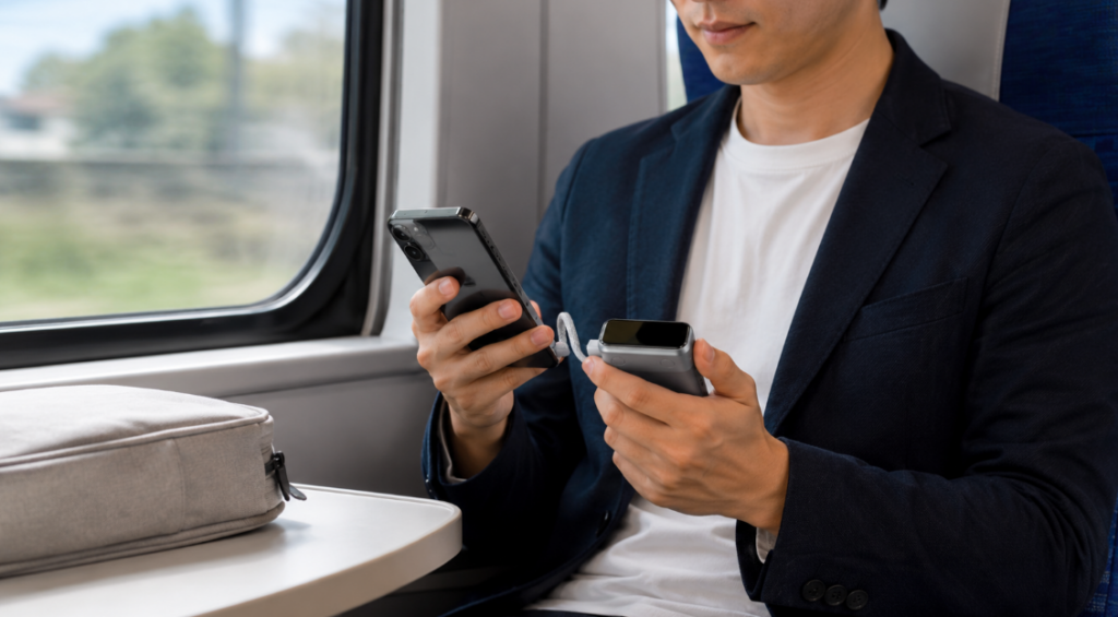 UGREEN Nexode Wavyの内蔵USB-Cケーブルでスマホを充電する外出中の男性
