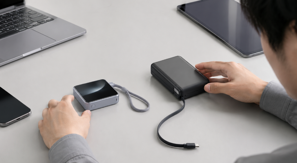 薄型UGREEN Nexode Wavyと巻取り式ケーブルのモバイルバッテリーを比較する様子