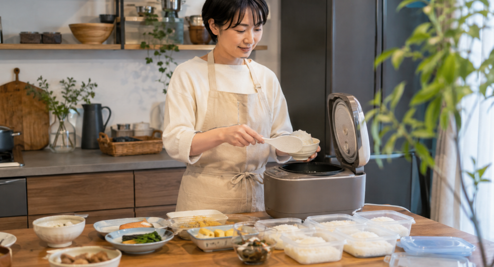 炊飯器のご飯を保存容器に小分けし冷凍ごはんを準備する日本人女性